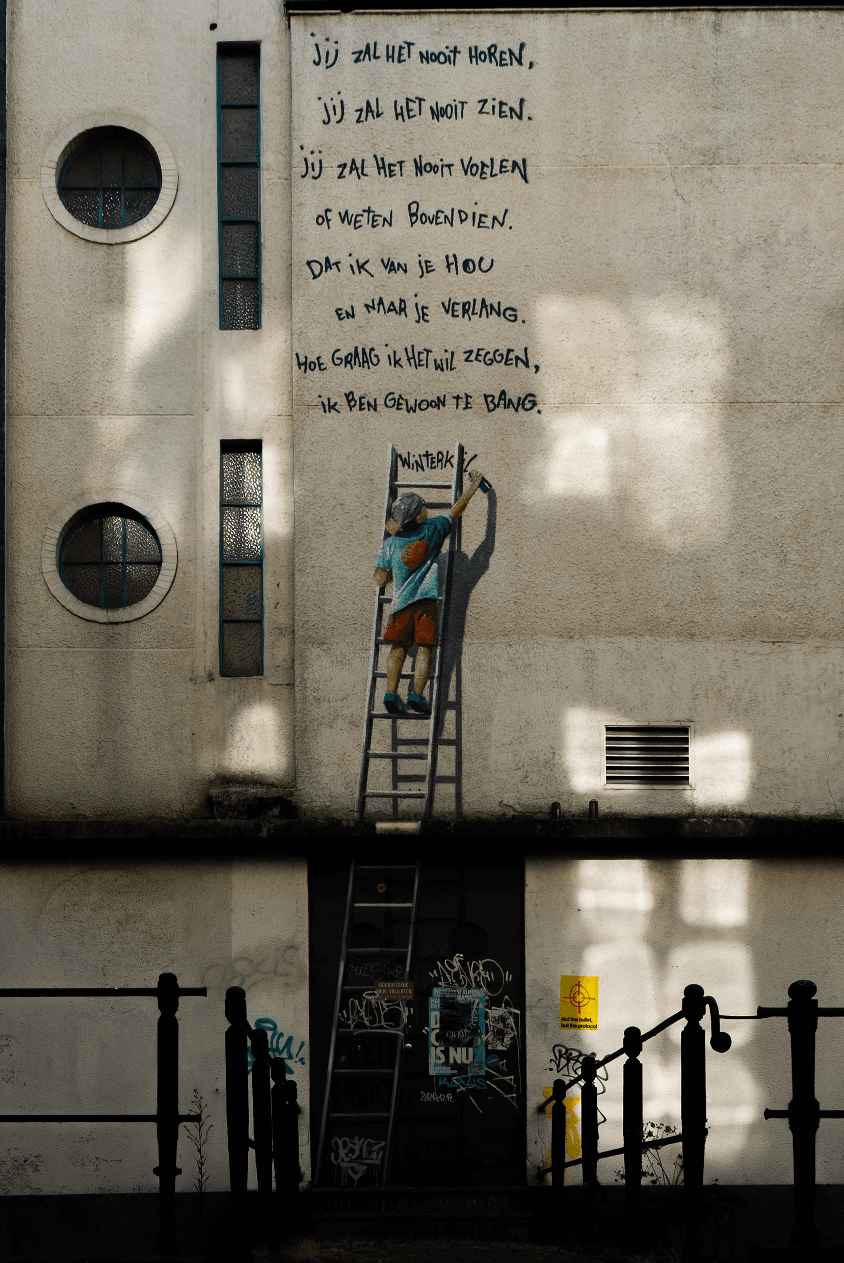 Een persoon op een ladder bij een gedicht op een muur